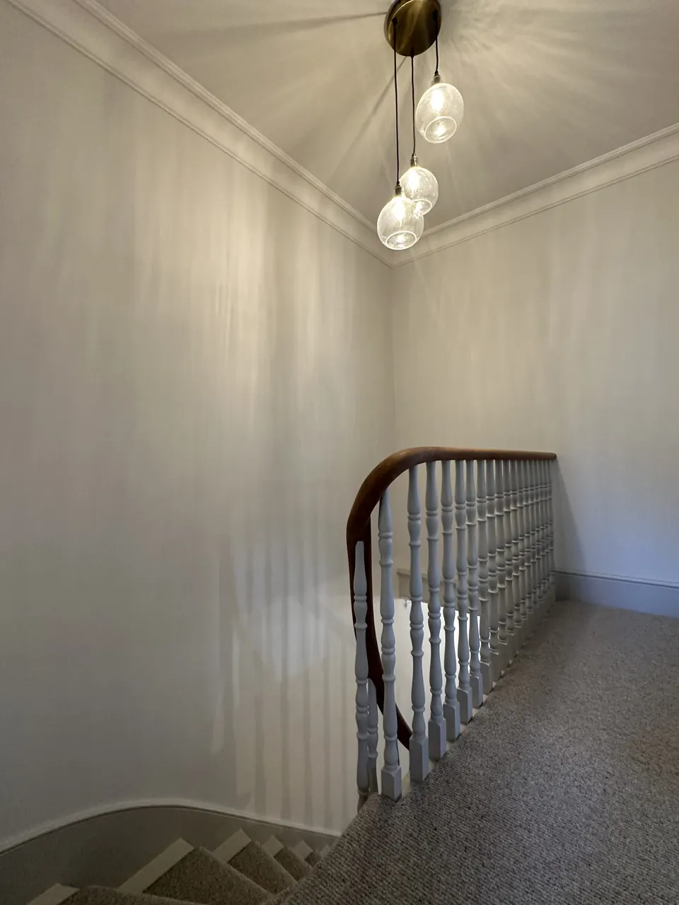 Landing with a glass pendant light above the restored staircase