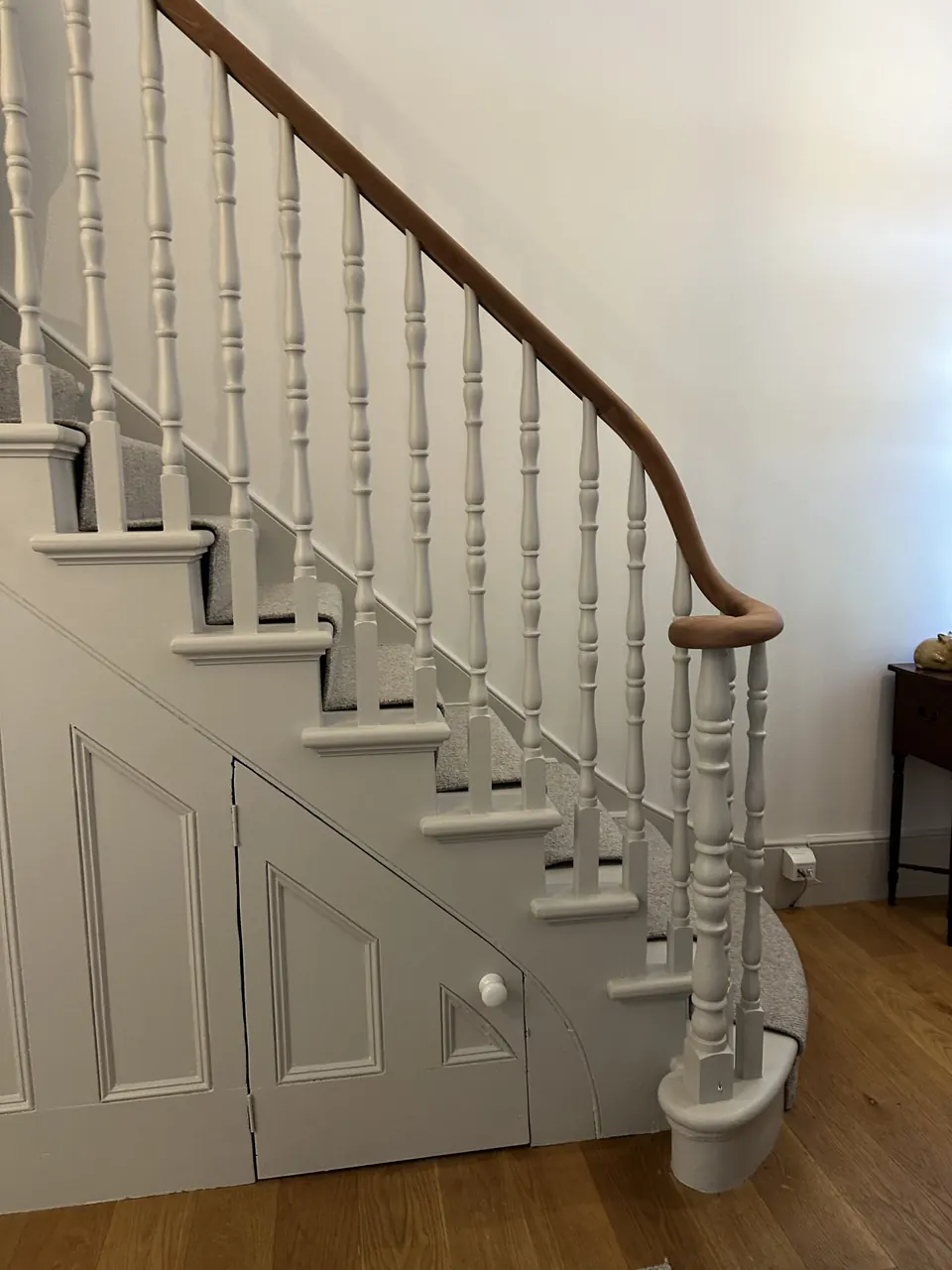 Restored staircase with white spindles and curved timber handrail