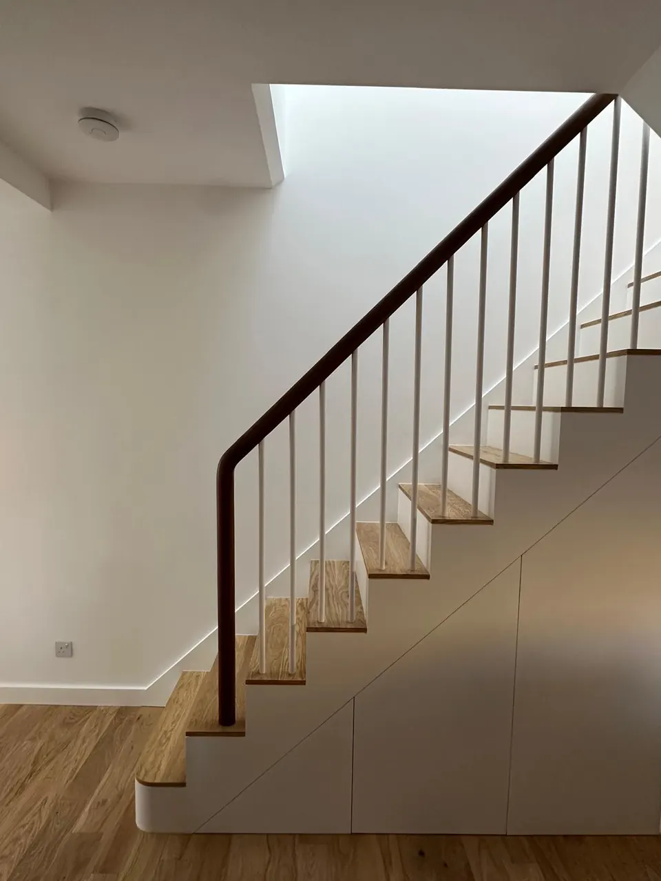 Oak staircase with slim black balustrade under a rooflight